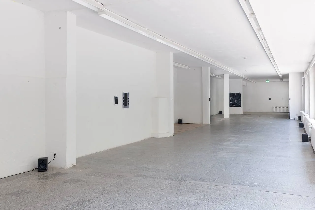 Exhibition view of Pro Max Ultra at Kunsthalle am Hamburger Platz: a long white hall with small speakers placed along the floor and walls